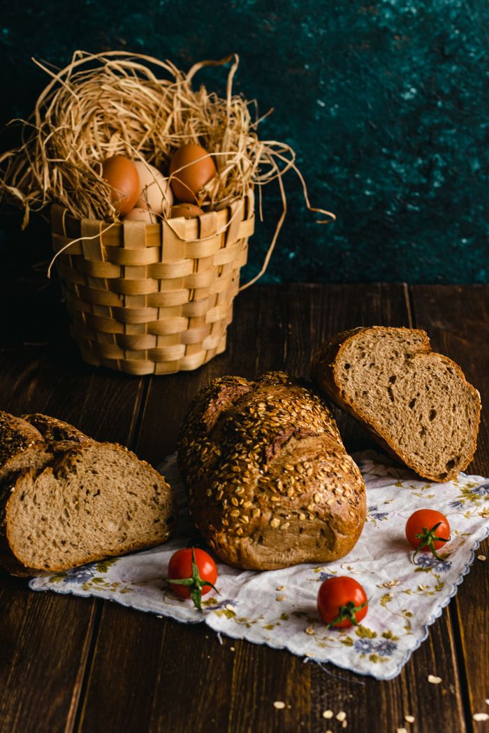 Artistic arrangement of whole grain bread, eggs, and tomatoes on a rustic background.